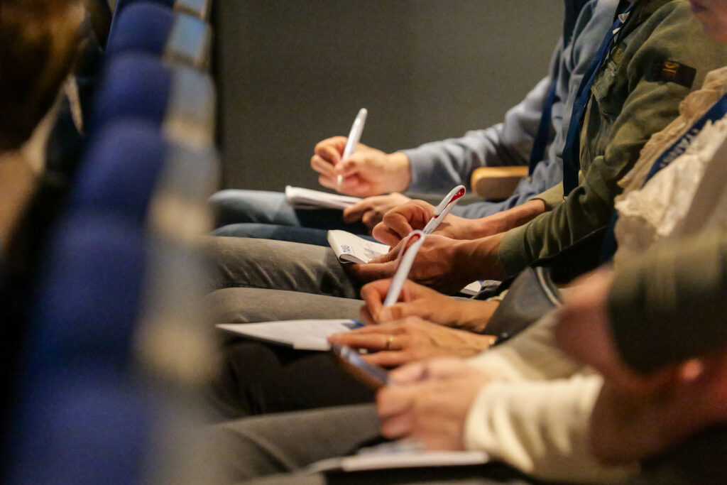 Deelnemers maken aantekeningen op papier tijdens een presentatie op het TANS Event van 10 april