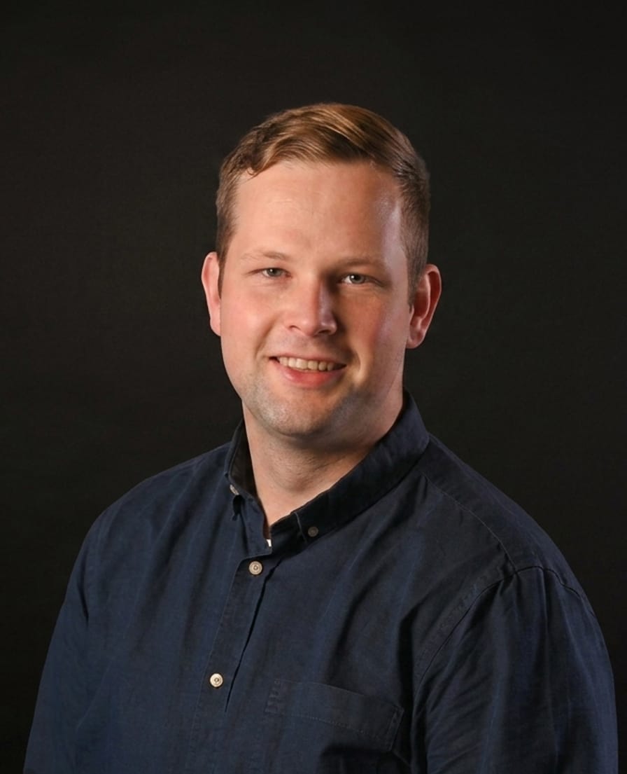 Portret van Luke in een donkerblauw overhemd tegen een grijze achtergrond