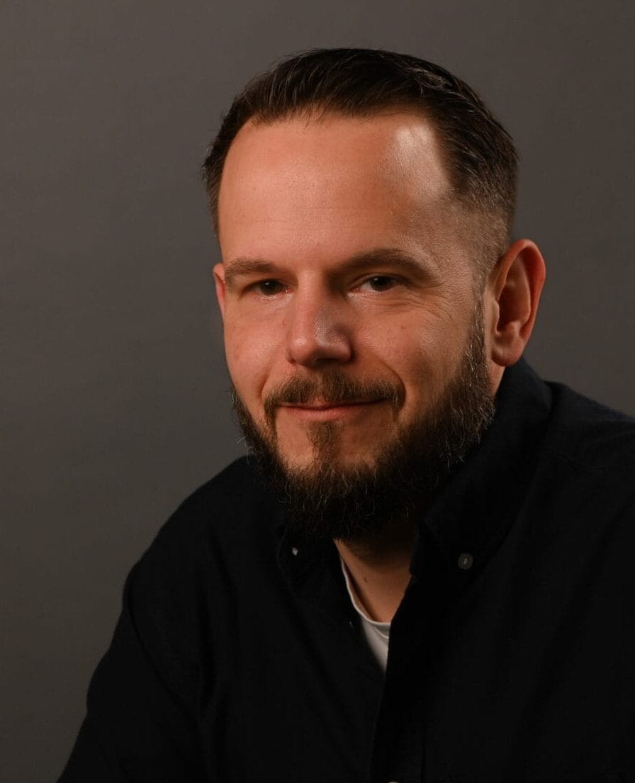 Portret van Robert in donker overhemd tegen een donkergrijze achtergrond