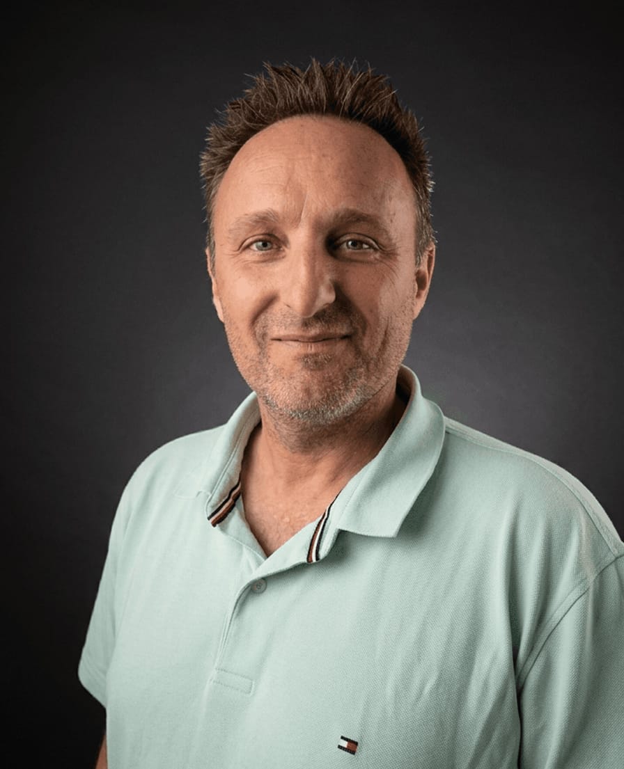 Portret van Wilfred in een mintgroen poloshirt tegen een donkere achtergrond
